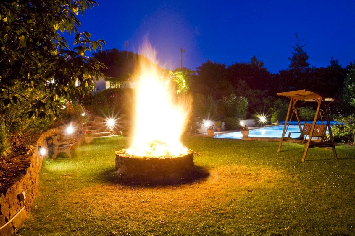 Summer fire pit beside floodlit swimming pool